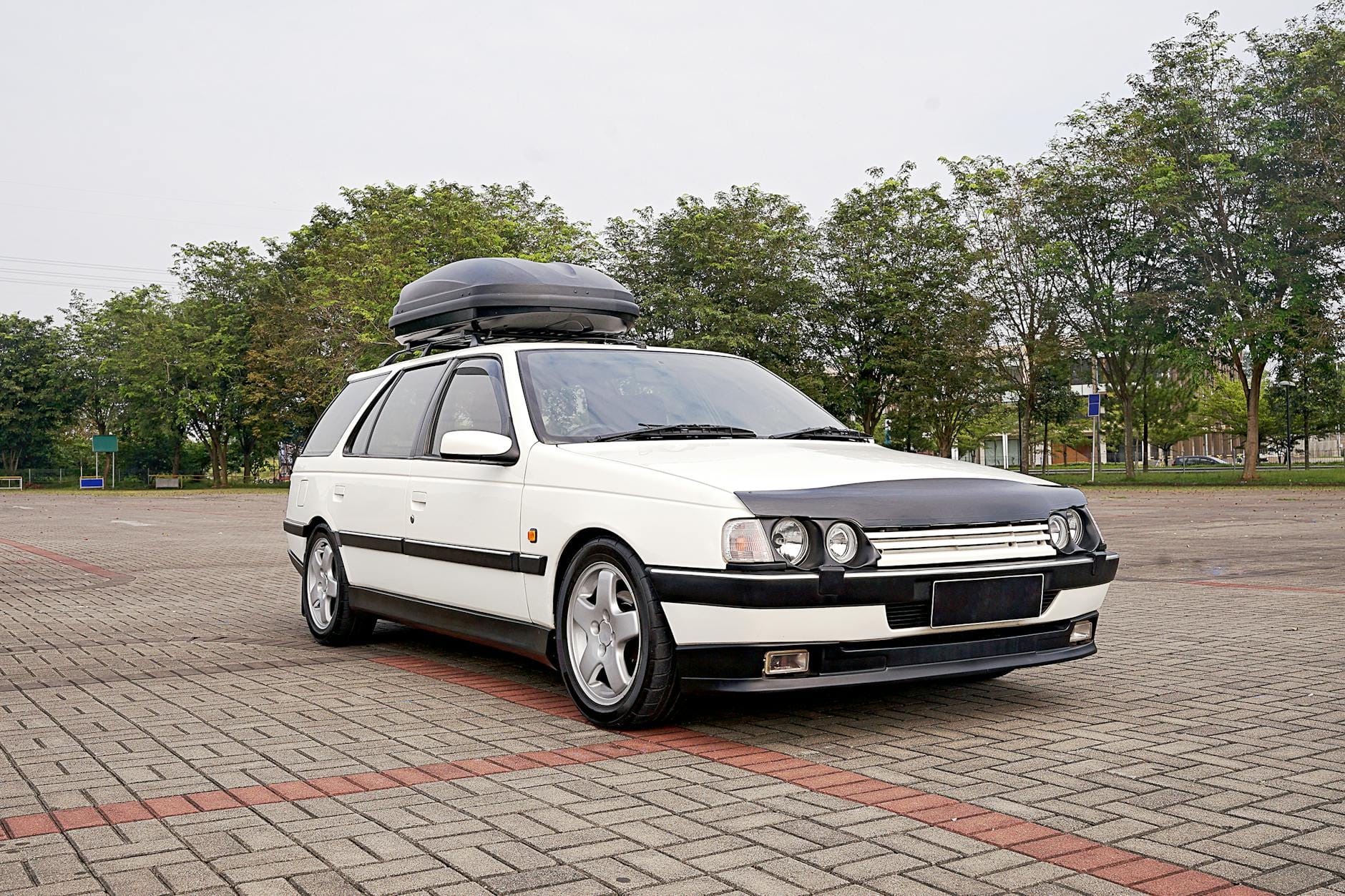 Białe kombi z boxem dachowym zaparkowane na ulicy