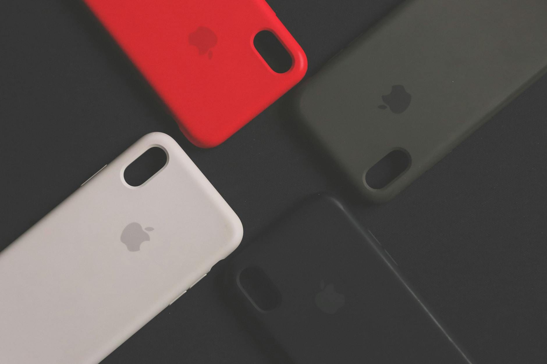 Cztery kolorowe pokrowce na smartfon ułożone na ciemnej powierzchni
