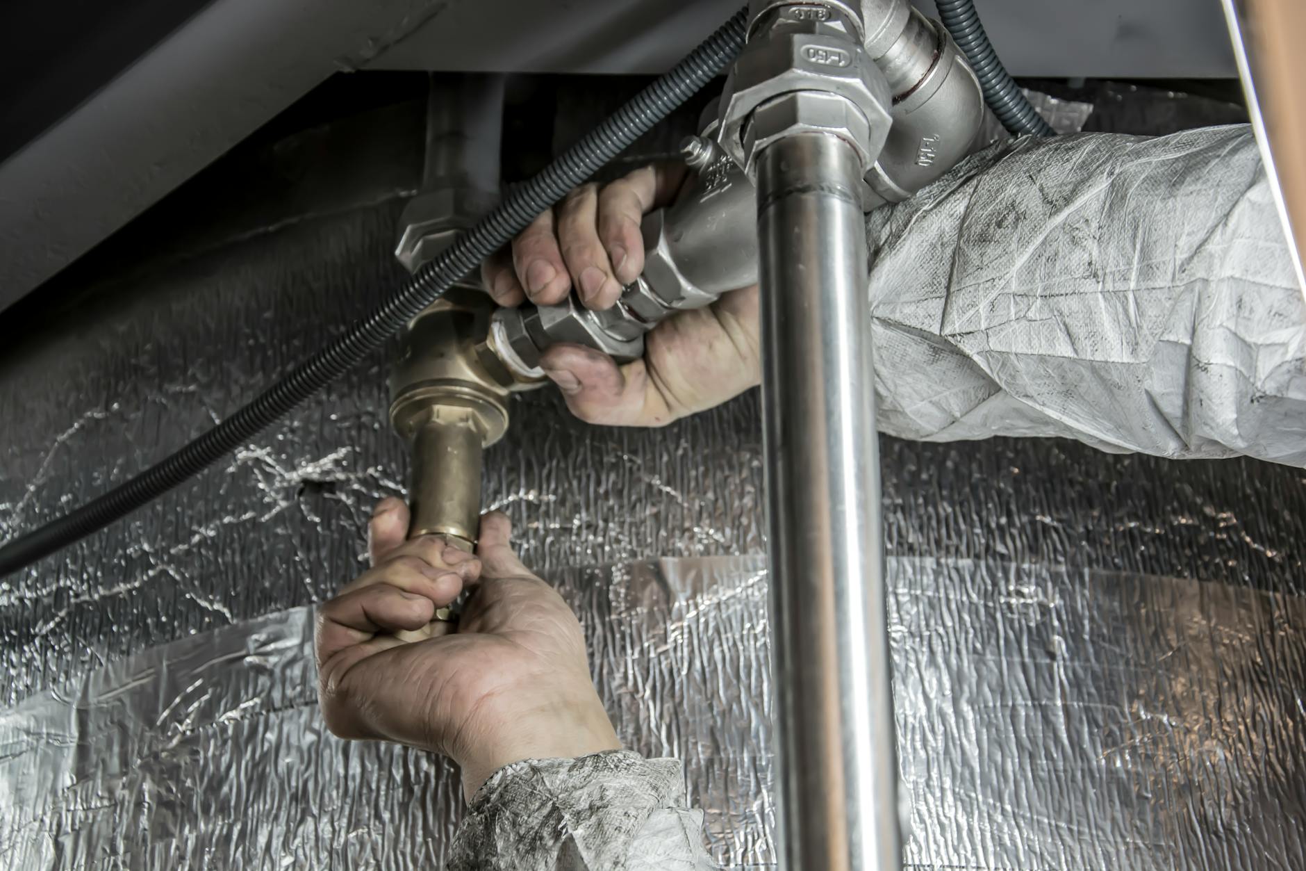 Ręce hydraulika montujące stalowe rury w łazience