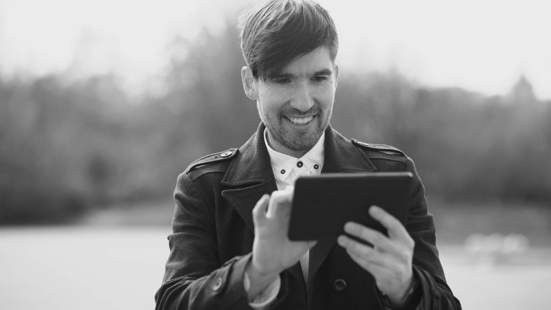 Uśmiechnięty mężczyzna z tabletem na dworze w czarno-białej fotografii