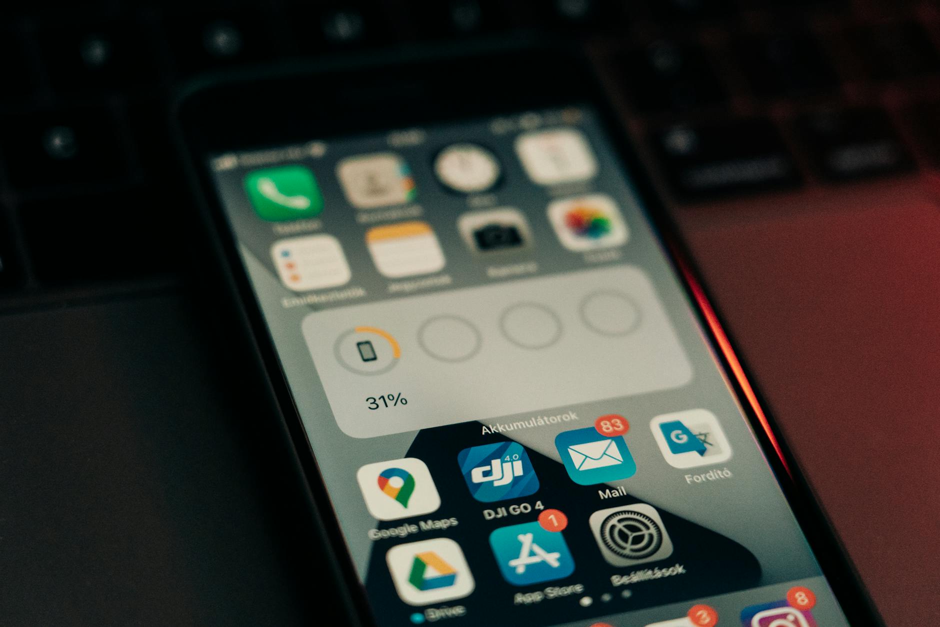 Smartfon z 31% baterii leżący na klawiaturze laptopa